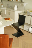 Modern kitchen with a black zigzag wooden chair, white countertop, and wooden floor.