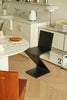 Modern kitchen with a black zigzag wooden chair, white countertop, and wooden floor.
