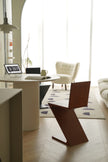 Modern interior with a brown wooden chair, round table, and white sofa.