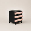 Black and pink drawer unit on wheels with a beige background