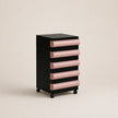 Black and pink drawer unit on wheels against a beige background