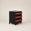 Black and red three-drawer cabinet on wheels with a beige background