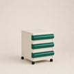 Small cabinet with green drawers on a beige background