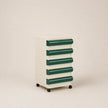 Small storage cabinet with green drawers on a beige background