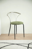 Metal dining room chair with green cushion on a wooden floor and light-colored wall background