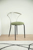 Metal dining room chair with green cushion on a wooden floor and light-colored wall background