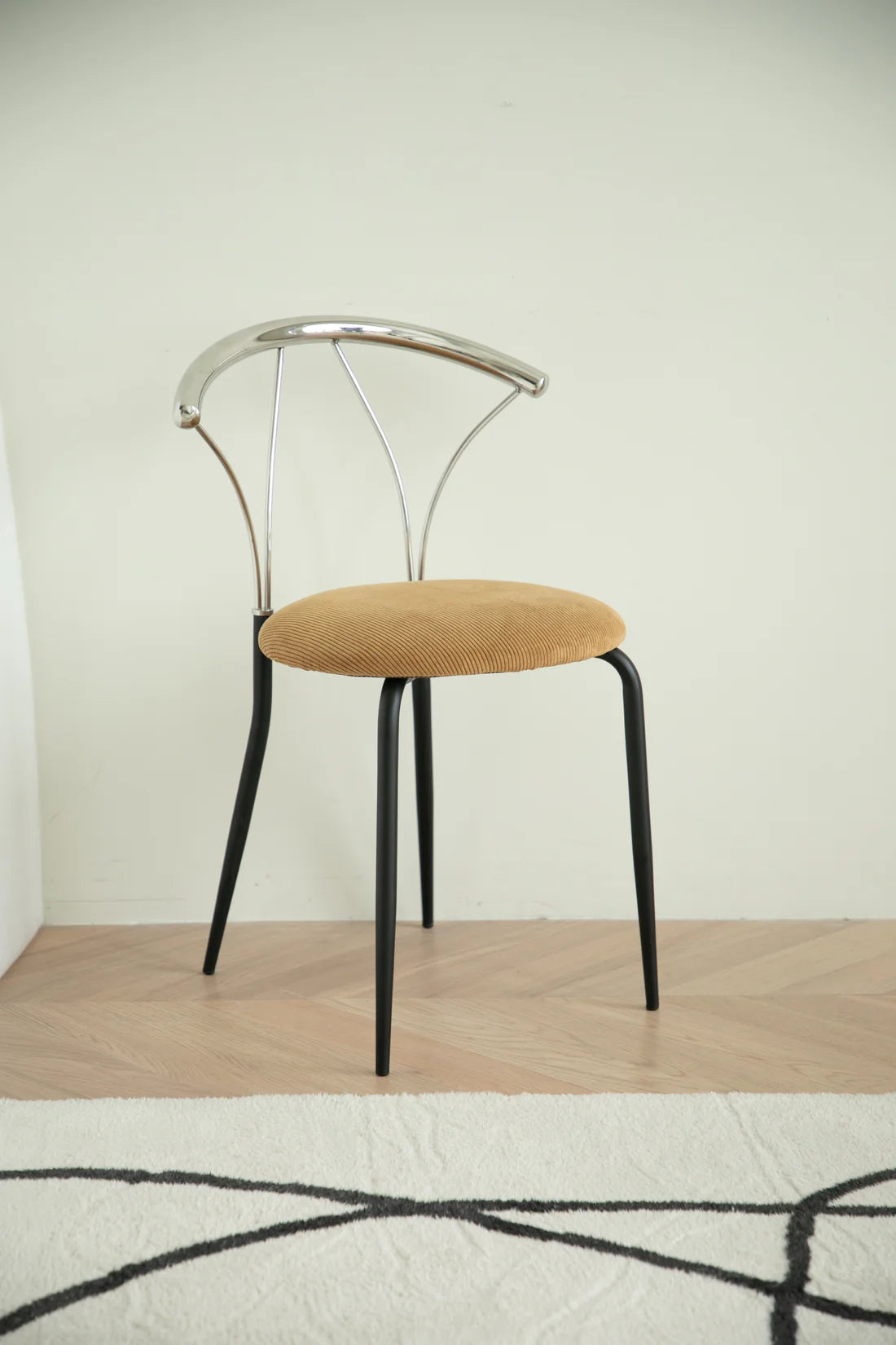 Metal chair with metal frame and beige cushion on a wooden floor.