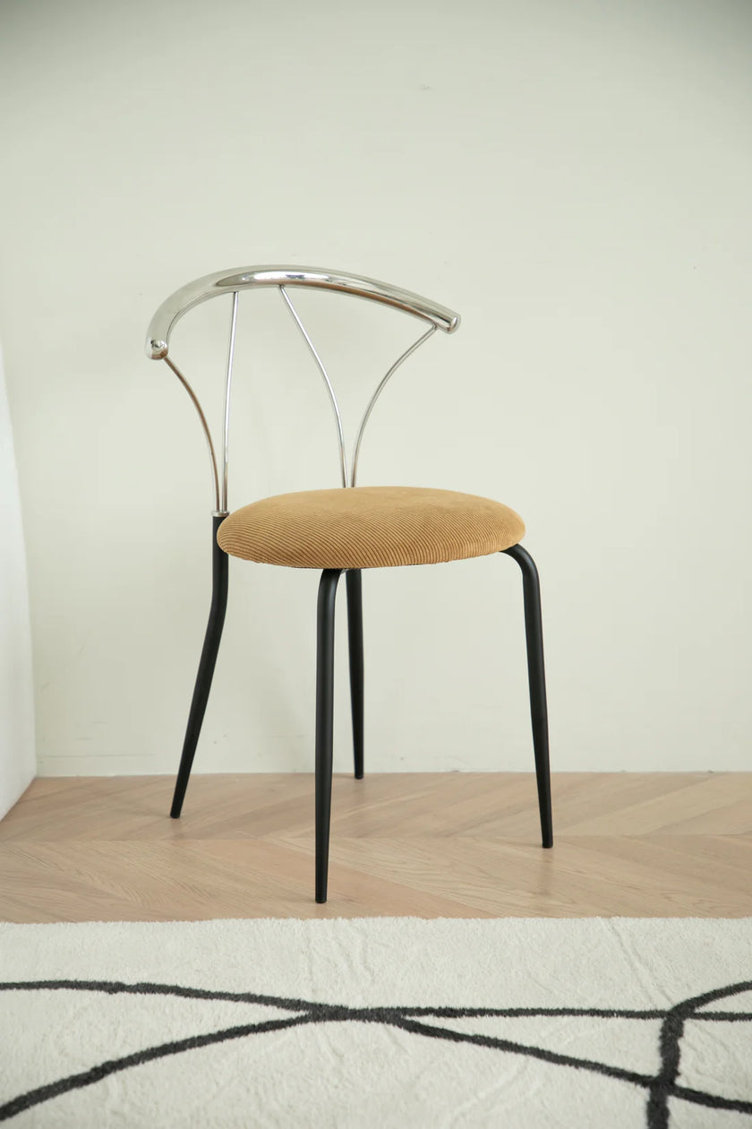 Metal chair with metal frame and beige cushion on a wooden floor.