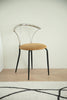 Metal chair with metal frame and beige cushion on a wooden floor.