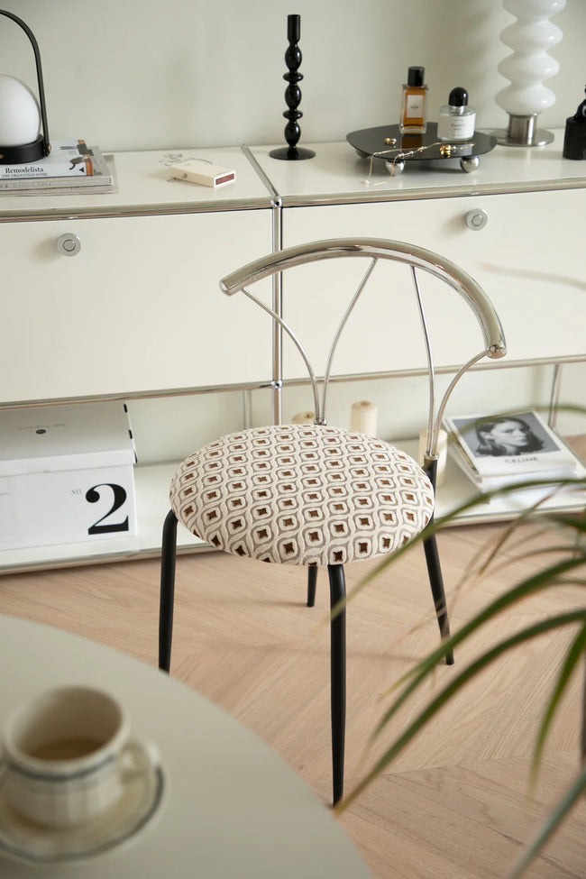 Comfy chair with patterned cushion in a room with a desk and decor items.