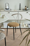 Modern chair with a beige cushion dining chair in a minimalistic room with white cabinets and a plant.