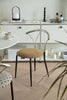 Modern chair with a beige cushion dining chair in a minimalistic room with white cabinets and a plant.