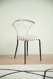 Metal chair with a patterned cushion on a wooden floor and light-colored wall background