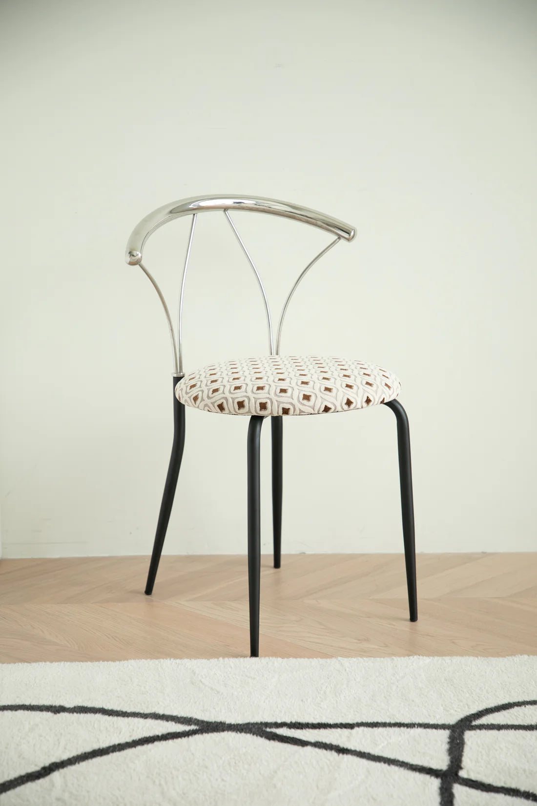 Metal chair with a patterned cushion on a wooden floor and light-colored wall background