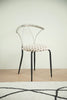 Metal chair with a patterned cushion on a wooden floor and light-colored wall background