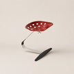 Red chair with a black footrest on a beige background