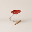 Red perforated chair with metal frame and wooden seat on a beige background