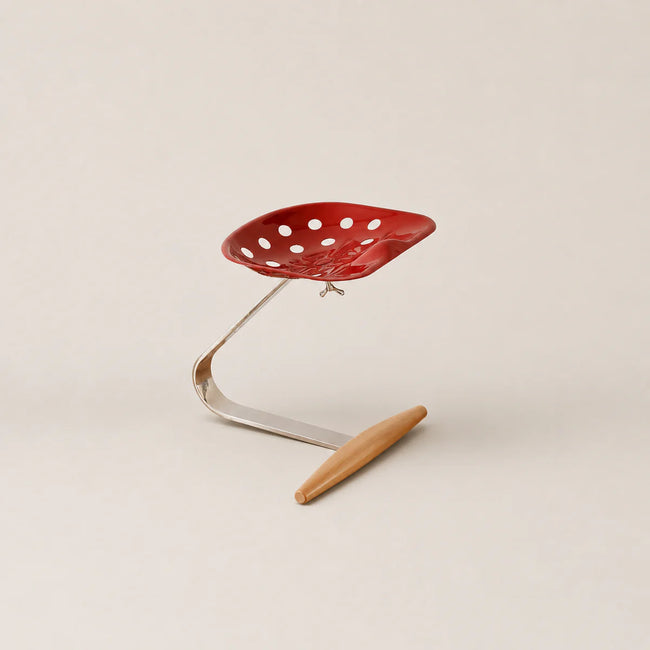 Red perforated chair with metal frame and wooden seat on a beige background