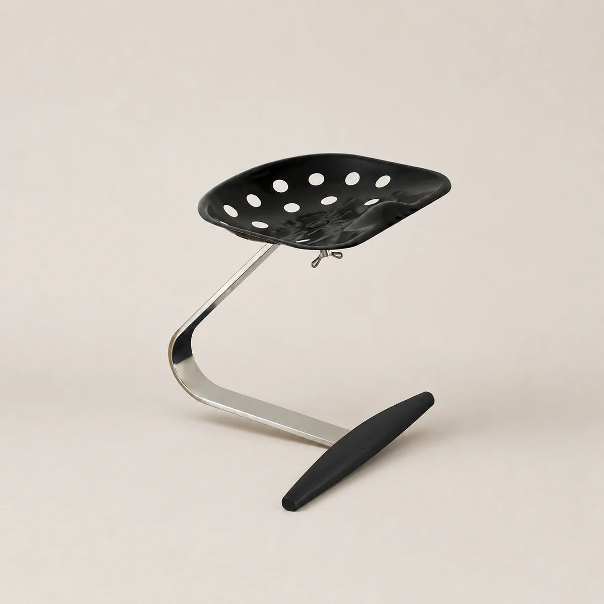 Black stool with perforated seat and curved metal frame on a beige background