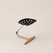 Black colander with a wooden handle on a beige background