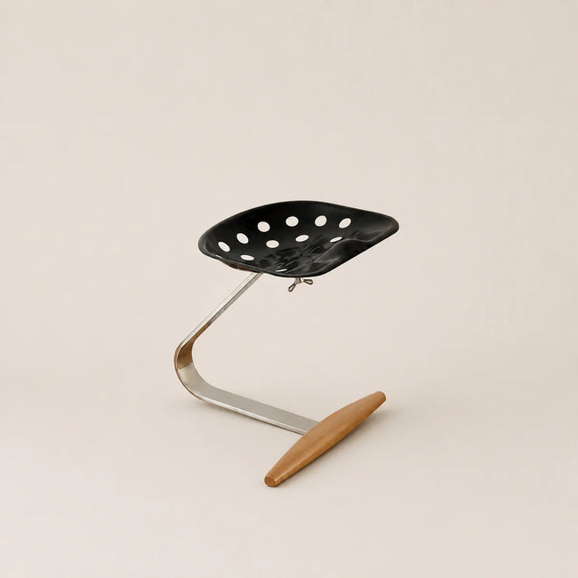 Black colander with a wooden handle on a beige background