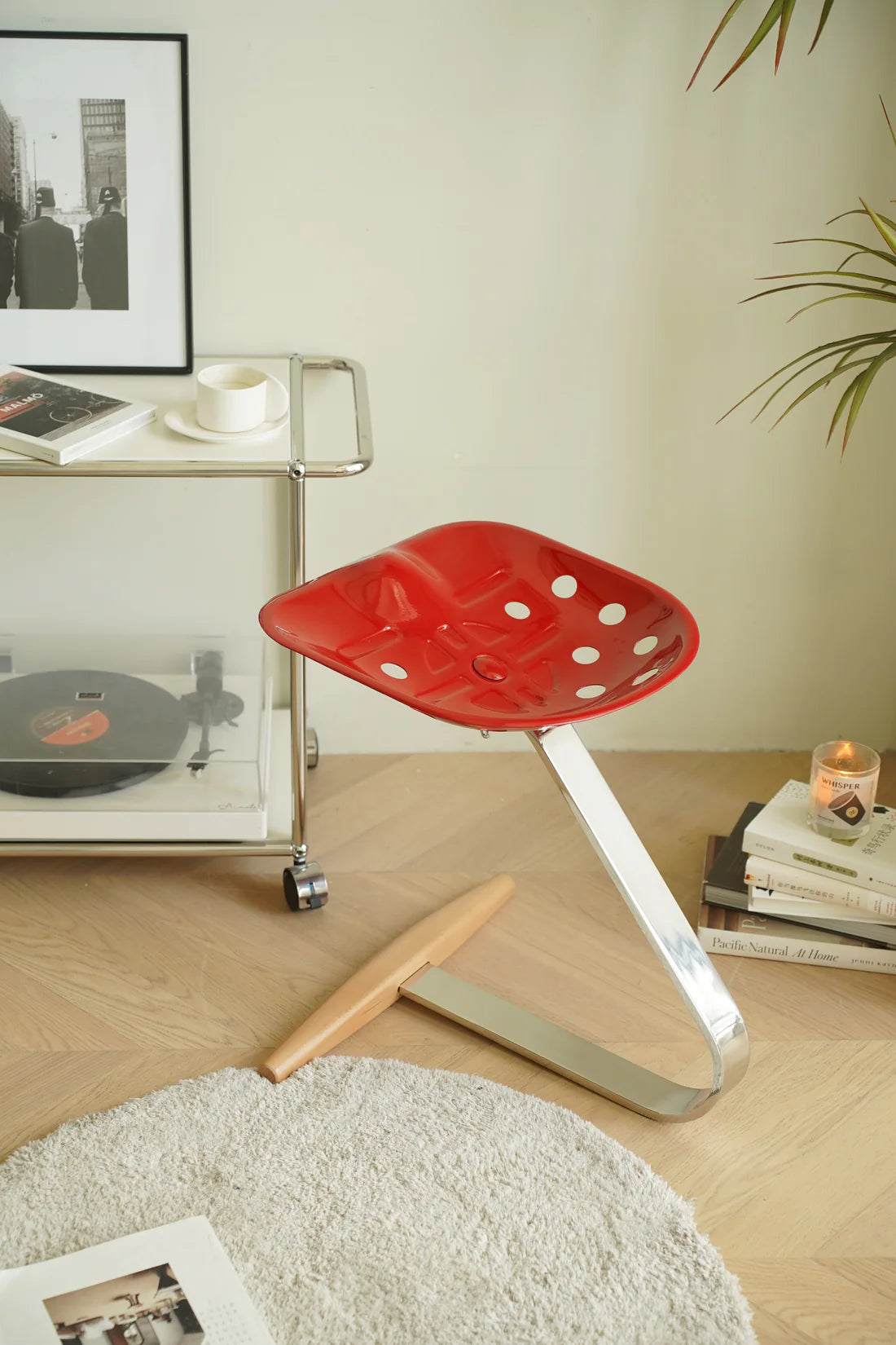 Red polka dot counter stool in a living room setting with a cart, books, and a candle.