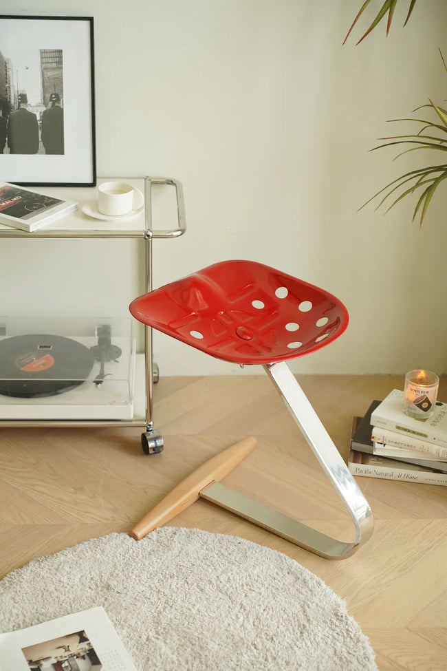 Red polka dot counter stool in a living room setting with a cart, books, and a candle.