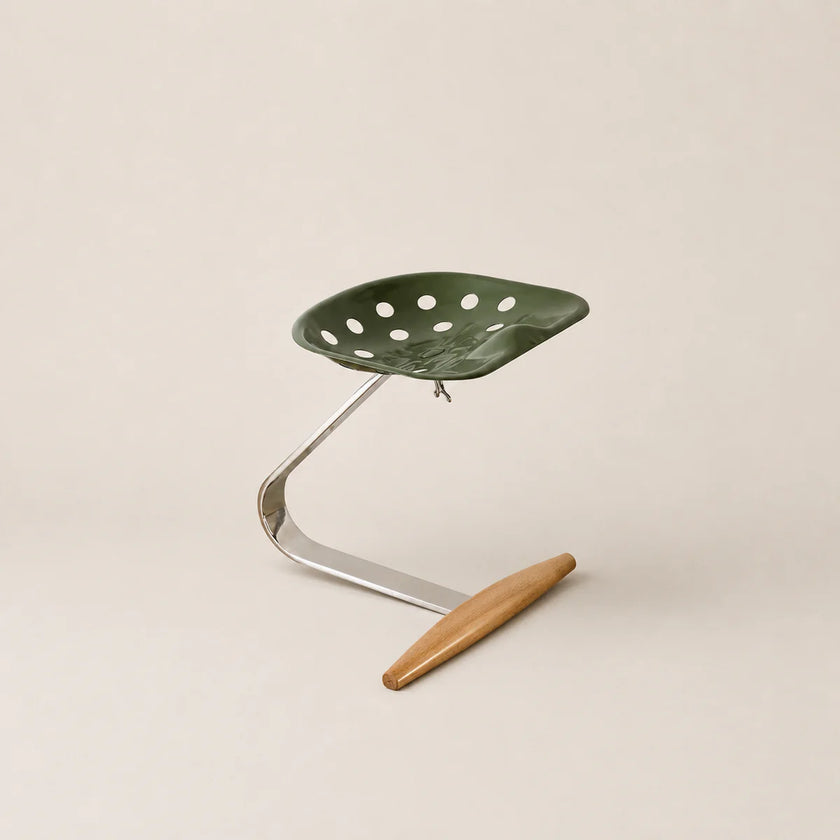 Green leaf-shaped stool with a wooden footrest on a beige background