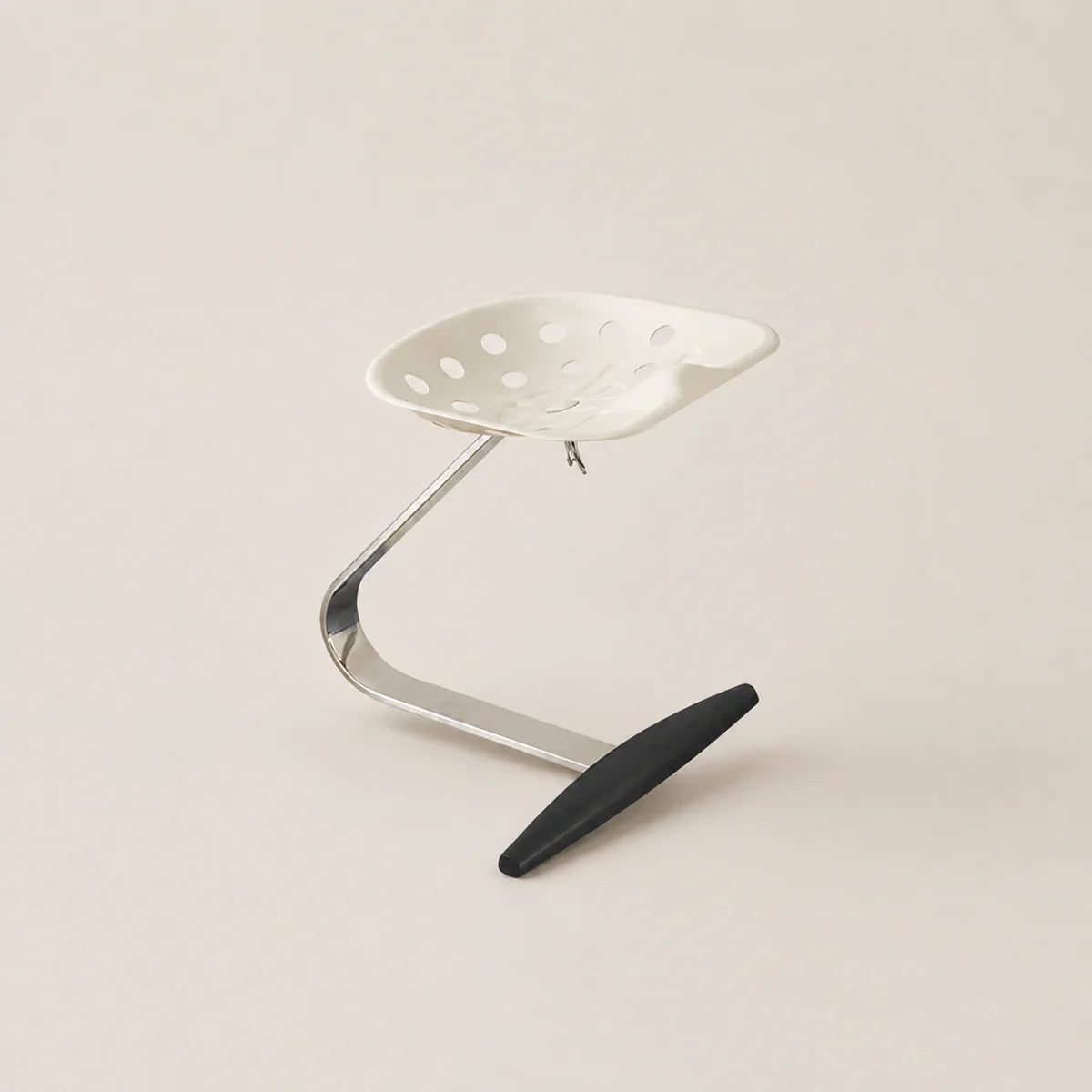 Metal stool with a black footrest on a beige background