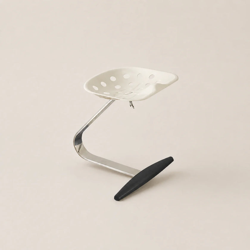 Metal stool with a black footrest on a beige background