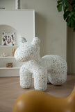Speckled white and gray decorative animal figure kids stool on a wooden floor with a shelf in the background.