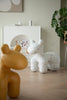 Two plastic kids chair sculptures, one yellow and one white with black speckles, on a wooden floor.