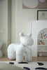 Speckled white and black animal sculpture plastic kids chair on a patterned rug with a shelf in the background.