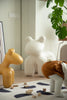 Children's room with large white bear-shaped kids stool, yellow giraffe-shaped living room chair, and child in brown pants.