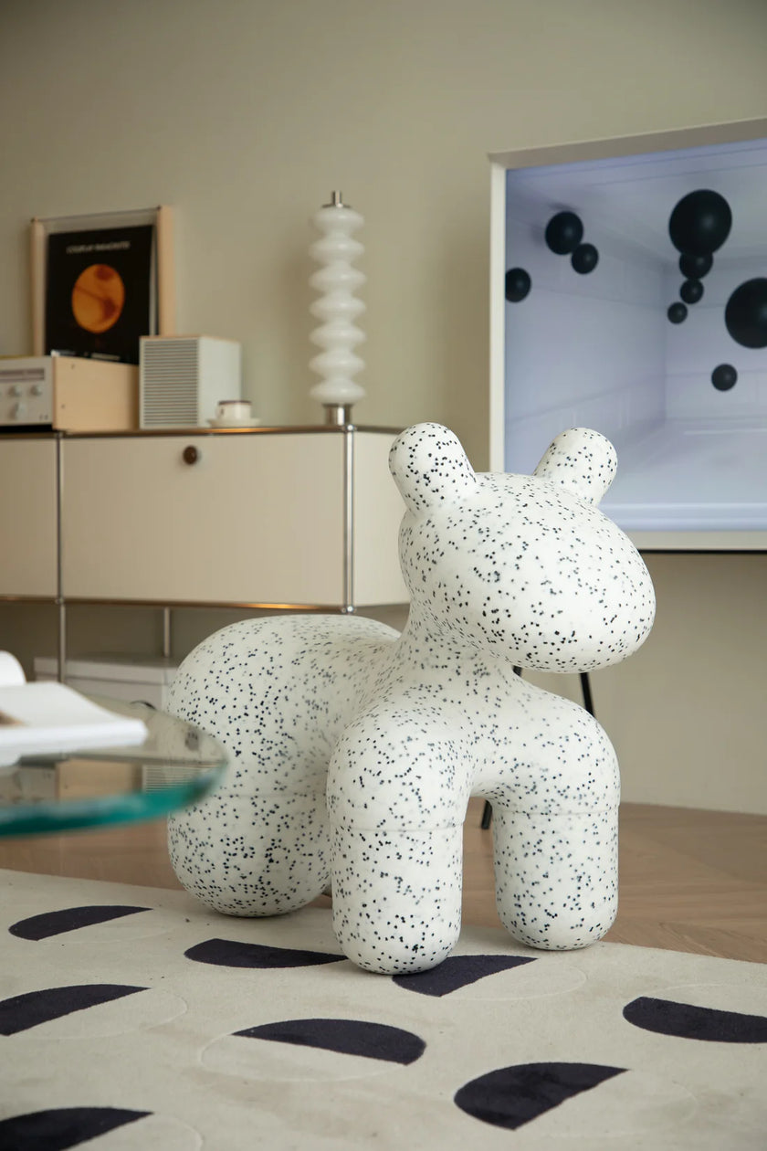 Speckled animal-shaped plastic kids stool in a modern interior setting with a television and cabinet.