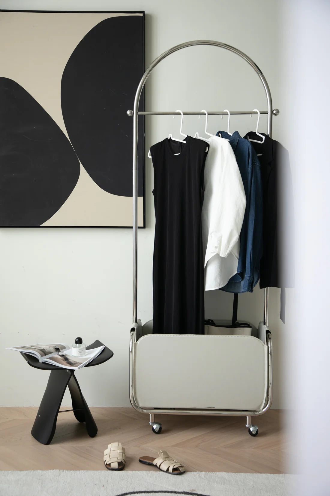 Clothing rack storage cube with clothes against a wall with abstract art