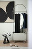 Clothing rack storage cube with clothes against a wall with abstract art
