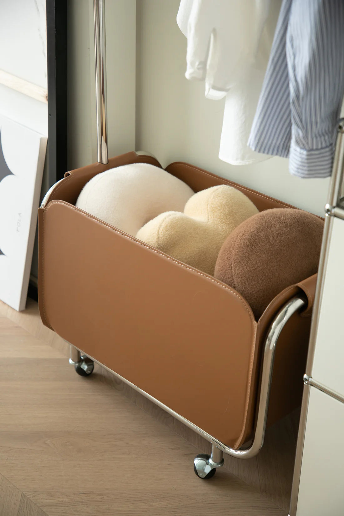 Modern brown rolling storage coat rack with wheels in a room setting