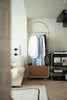 Modern room with a clothing modern coat rack, white chair, and small table with decor items.