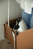 Close-up of a brown storage coat rack with a white bag inside, against a neutral background.