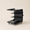 Black service cart with shelves on a beige background