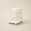 White rolling cart with multiple shelves on a beige background