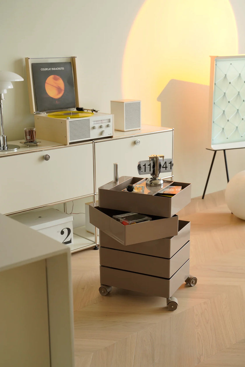 Modern kitchen with a coffee machine on a plastic containers rolling cart, light-colored cabinets, and decorative elements.