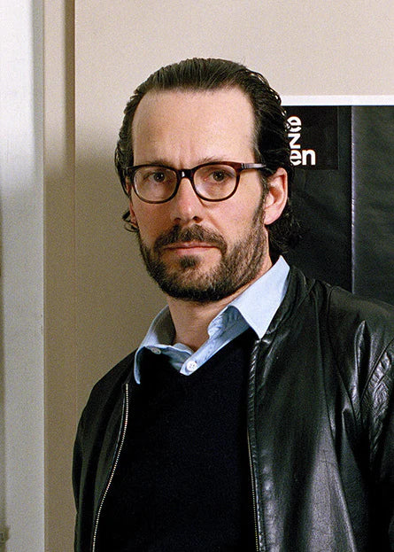 Man wearing glasses and a black leather jacket indoors