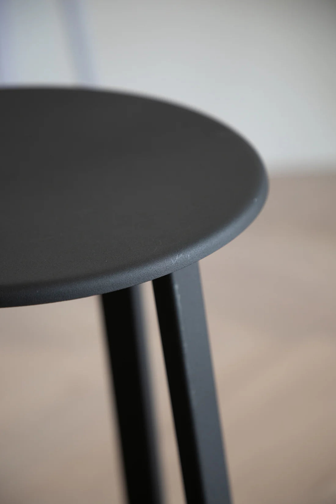 Black round bar stool with a blurred background.