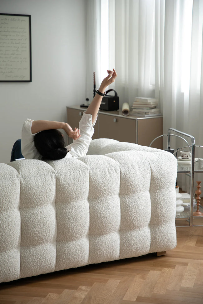 Women sitting on a white sofa in a modern living room with light decor.
