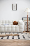 Modern living room with a white lounge sofa, patterned rug, and lamp.
