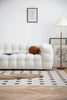Modern living room with a white lounge sofa, patterned rug, and lamp.