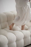 Lady wearing a white dress standing on a textured white sofa