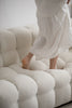 Lady wearing a white dress standing on a textured white sofa